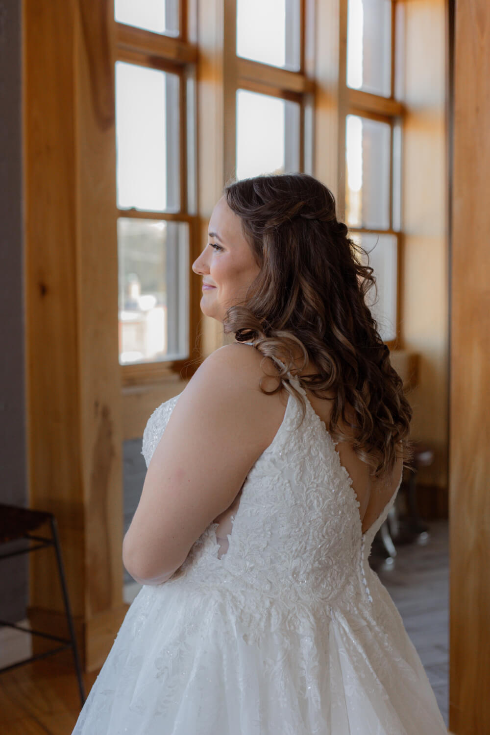 woman in a wedding dress smiling and looking out the window